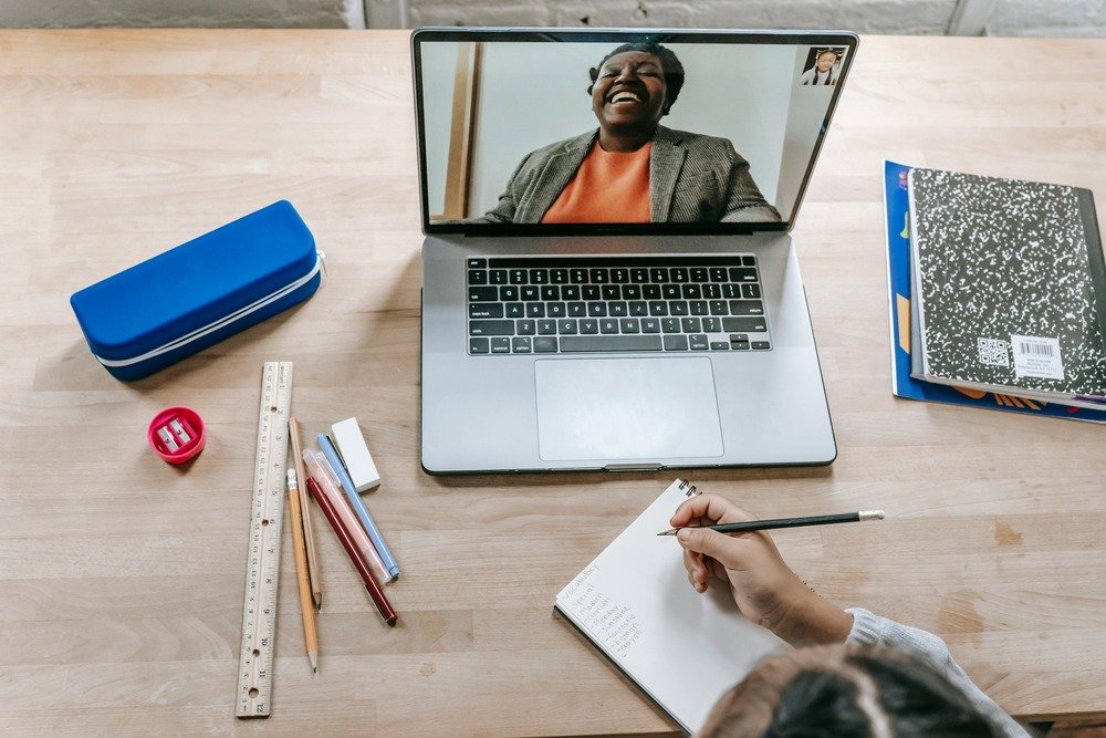 woman laughing on a laptop, someone taking notes in a notebook