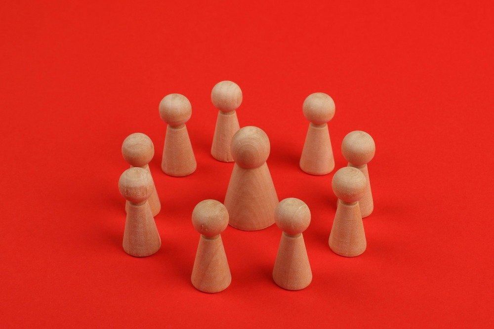 Wooden chess pawn pieces in a circle around a larger pawn piece